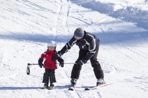 Kind mit Erwachsenen beim Skifahren lernen im Skiurlaub mit Kindern